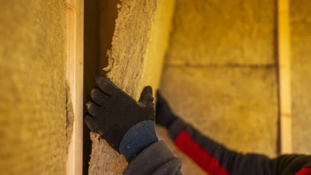 Worker installing thermal wall insulation materials.