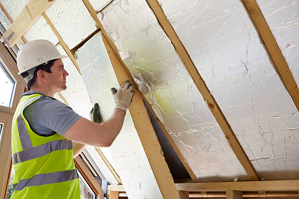 Worker installing thermal insulation for roofing sheet.