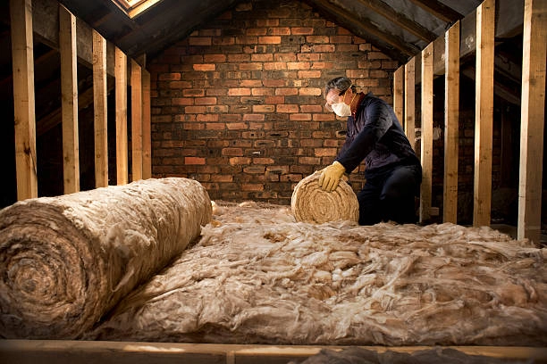 Worker installing rock wool board insulation in an attic.