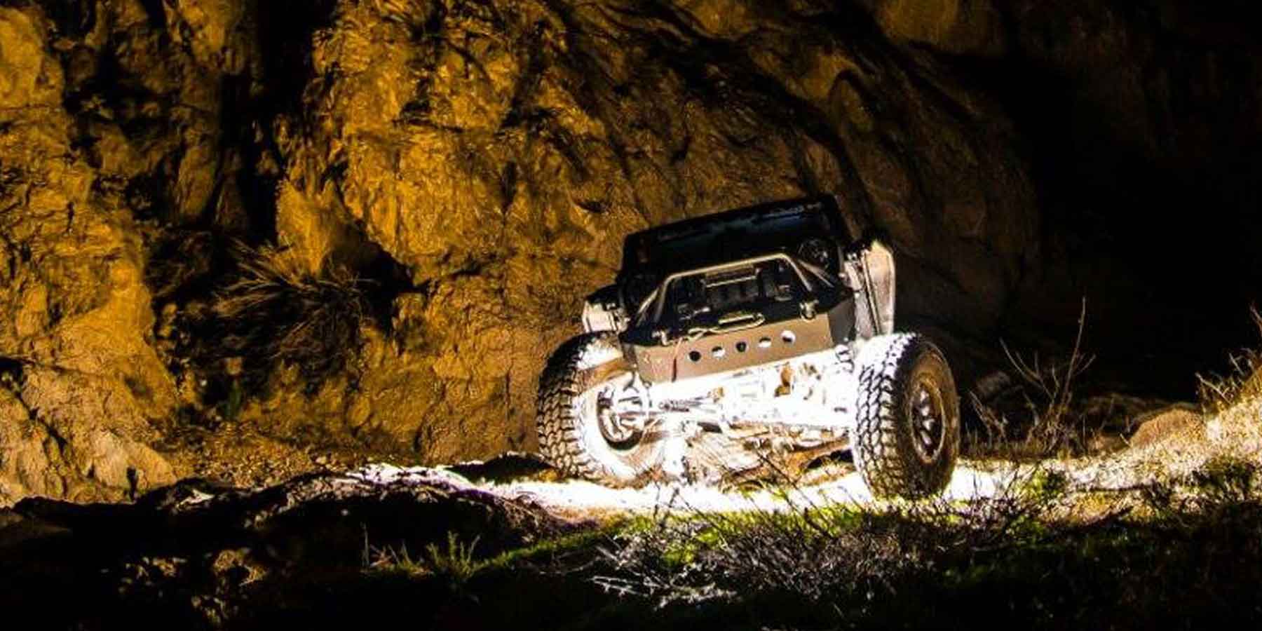 Off-road vehicle with LED rock light near a rock.