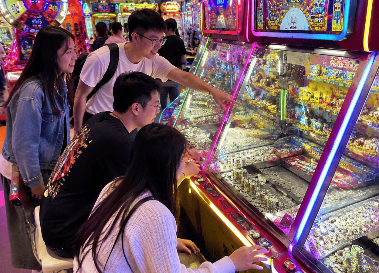 players enjoying coin pusher game in modern arcade center with LED machines
