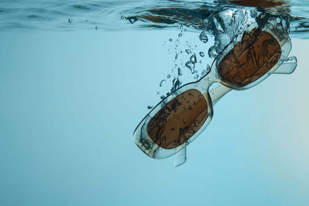 A pair of sunglasses falling into clear blue water with air bubbles. A pair of sunglasses falling into clear blue water with air bubbles.