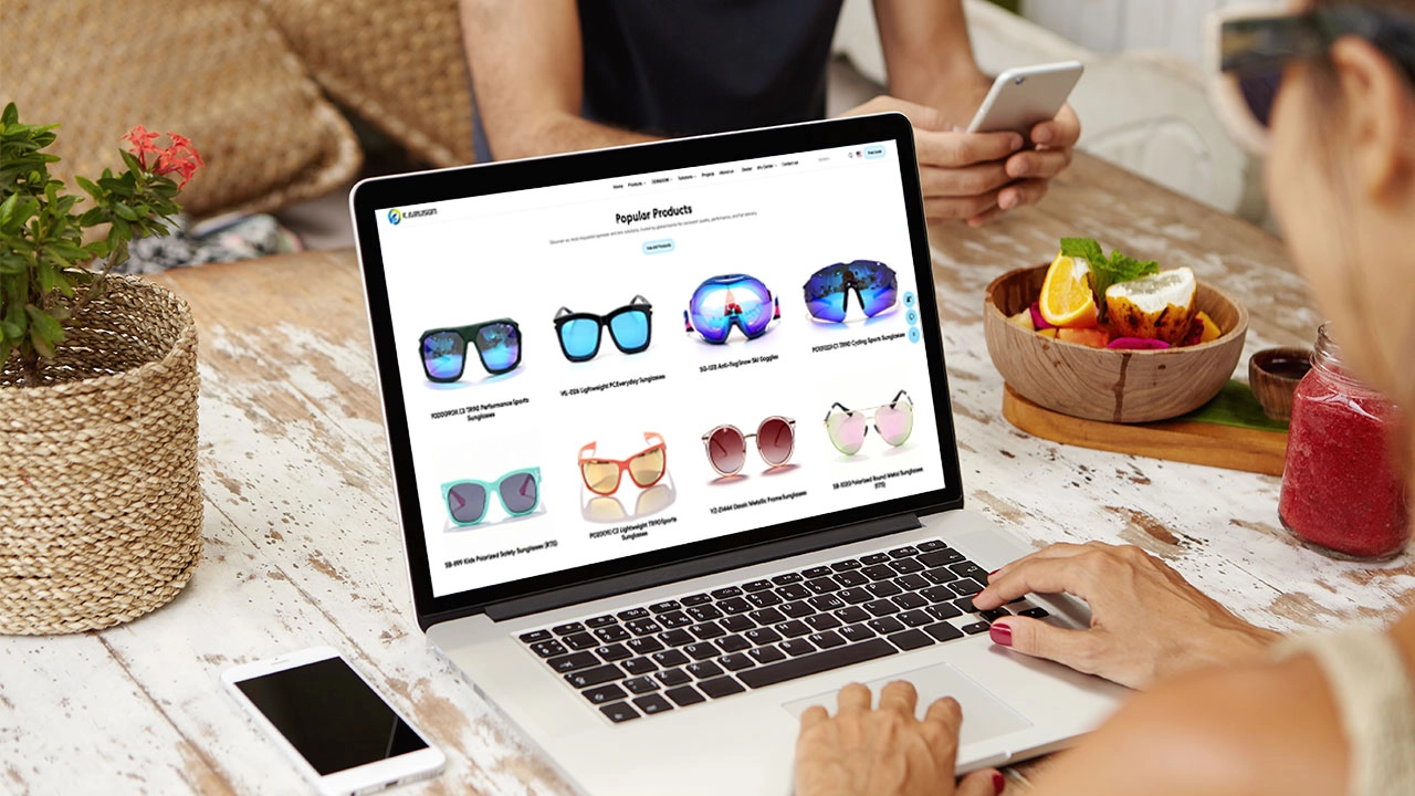 Woman browsing sunglasses on a laptop while at an outdoor table. - KARUSON