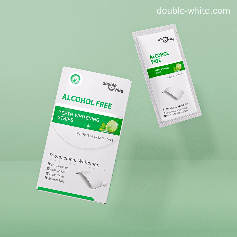 bandes-blanchissantes-sûres-pour-les-dents Une boîte de bandes de blanchiment des dents Double White contenant 28 bandes pour 14 traitements. Les bandes sont sans alcool et ont une saveur de menthe fraîche. L'emballage est blanc avec des accents verts et affiche le nom du produit, le logo et d'autres informations.