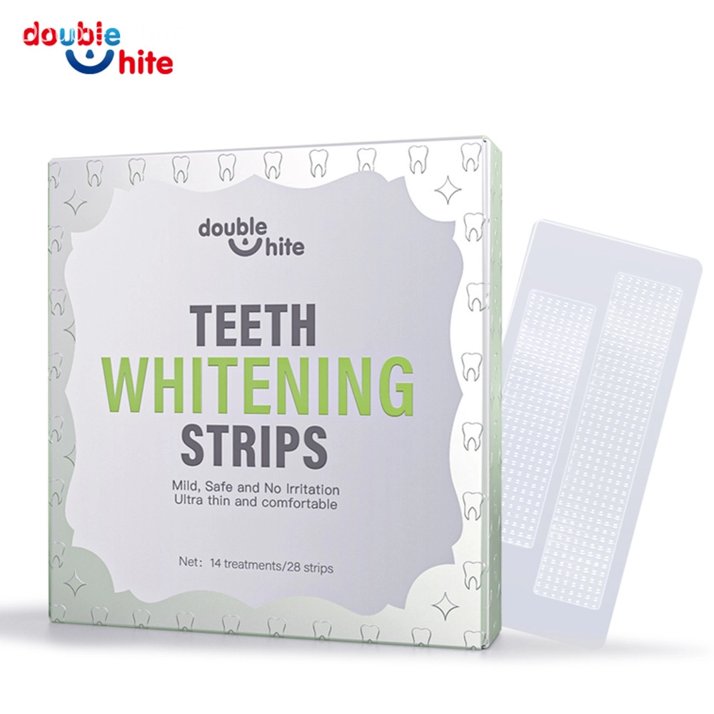 Uma caixa de tiras de clareamento dental Double White. A caixa é branca com texto verde e um desenho de folha verde. A frente da caixa exibe o nome do produto, o logotipo e uma lista dos benefícios do produto.