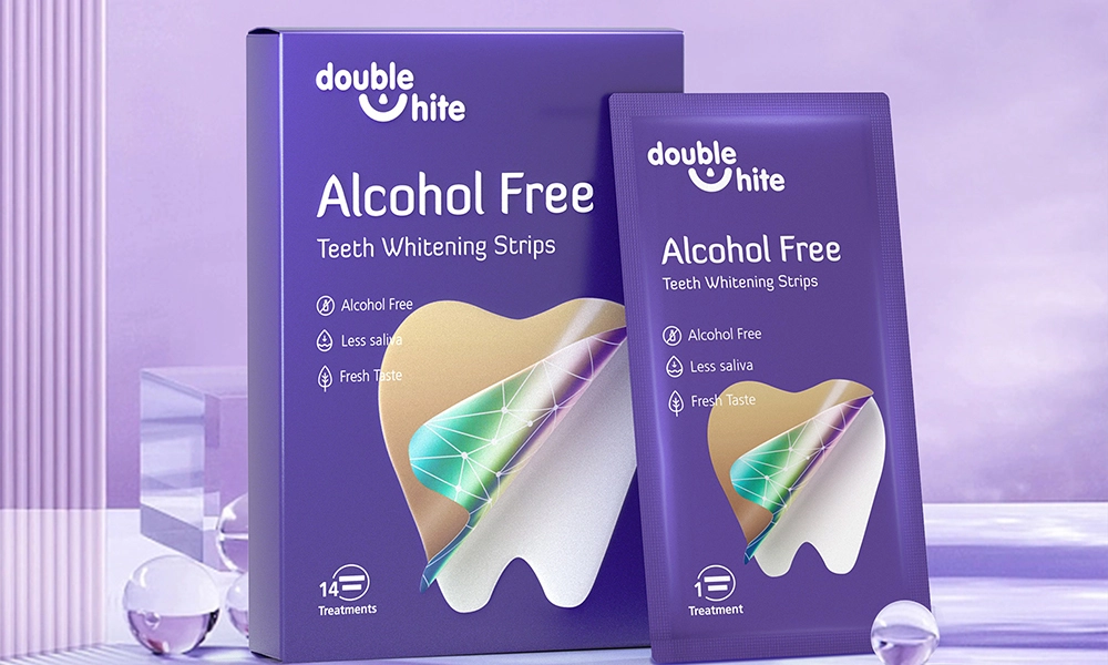 Uma caixa de Double White Alcohol-Free Teeth Whitening Strips. A caixa é roxa e branca, com uma janela transparente na frente mostrando as tiras dentro. As tiras são embaladas individualmente em pacotes de papel alumínio.