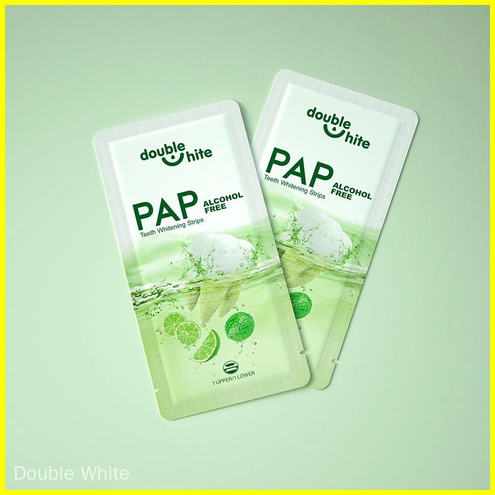 Two green and white Double White PAP Teeth Whitening Strips packages on a green background.