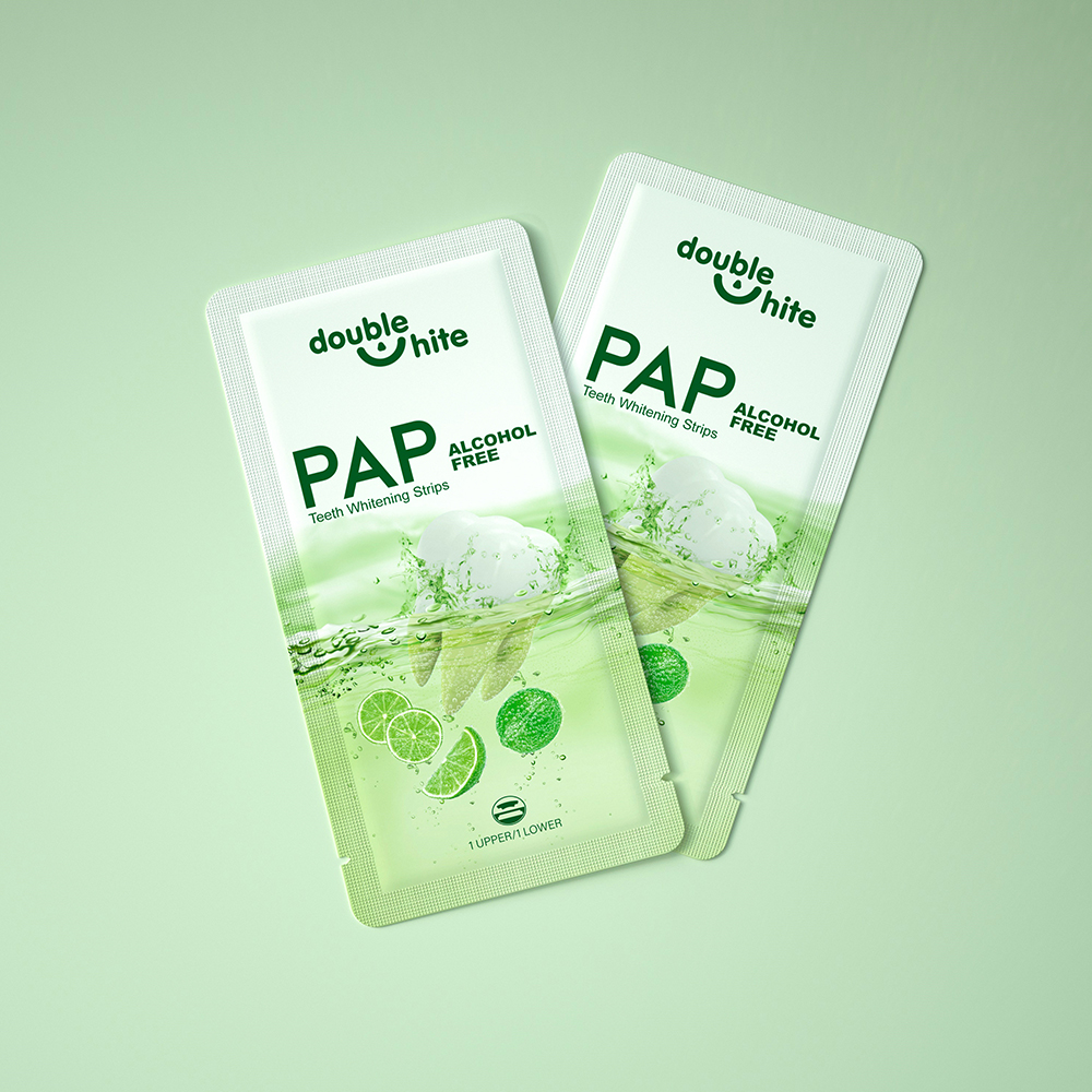 Two green and white Double White PAP Teeth Whitening Strips packages on a green background.