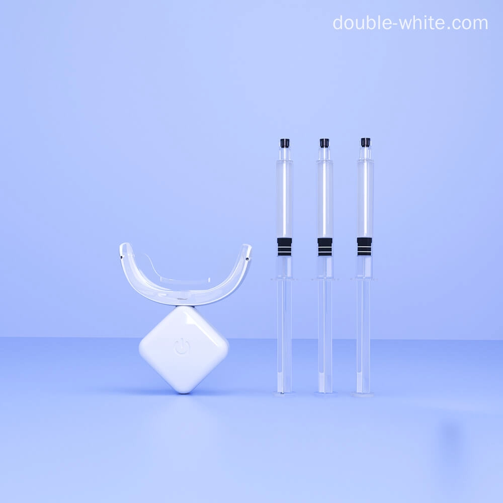 Three whitening gel syringes and a teeth whitening LED light on a blue background.