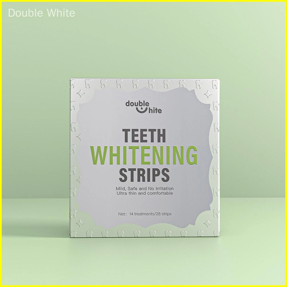 Uma caixa de tiras de clareamento dental Double White. A caixa é branca com texto verde e um desenho de folha verde. A frente da caixa exibe o nome do produto, o logotipo e uma lista dos benefícios do produto.