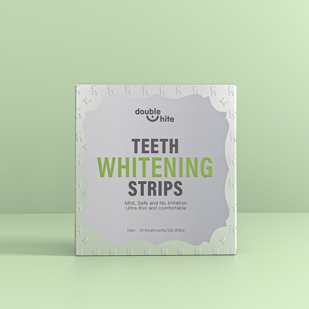 Una caja de tiras blanqueadoras de dientes Double White. La caja es blanca con texto verde y un diseño de hojas verdes. En el frente de la caja se muestra el nombre del producto, el logotipo y una lista de los beneficios del producto.