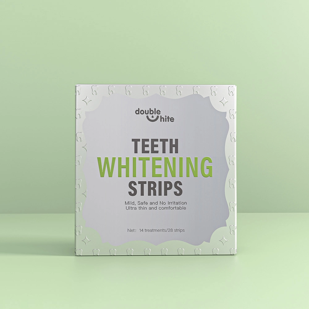 Una caja de tiras blanqueadoras de dientes Double White. La caja es blanca con texto verde y un diseño de hojas verdes. En el frente de la caja se muestra el nombre del producto, el logotipo y una lista de los beneficios del producto.