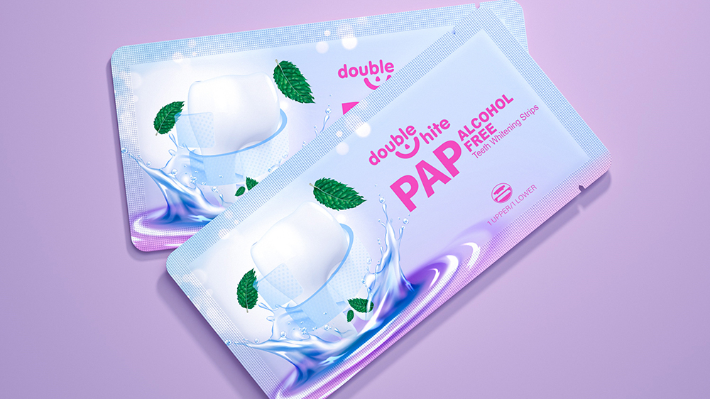 A product image of Double White PAP Free Alcohol Free Teeth Whitening Strips. The packaging is white and purple with a picture of a smiling mouth with two green mint leaves.