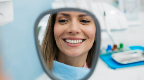 Mulher admirando seu sorriso brilhante após usar o melhor gel clareador para dentes sensíveis.