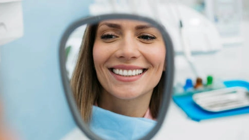 Woman admiring her bright smile after using best teeth whitening gel for sensitive teeth.