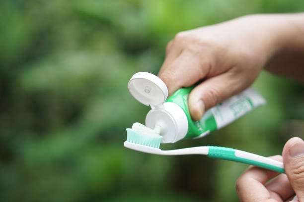 Hand squeezing Fluoride toothpaste onto toothbrush.