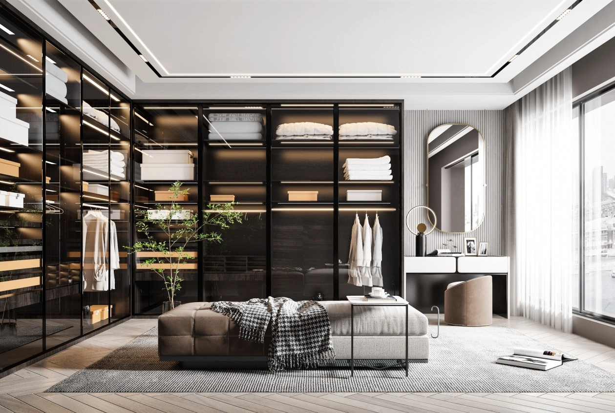 Modern walk-in closet with black-framed glass cabinets, central ottoman, and vanity area.