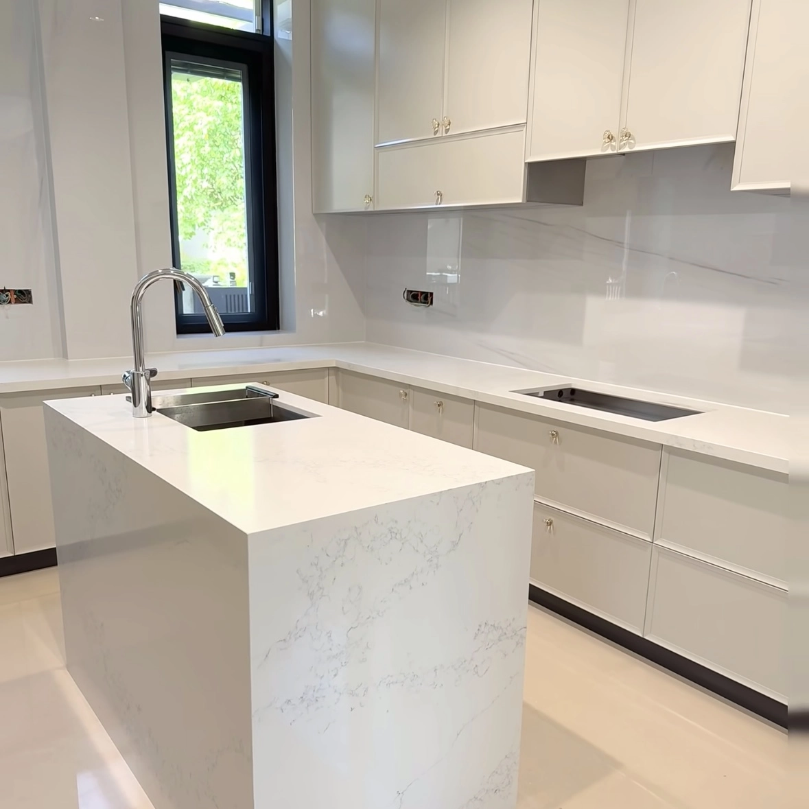 Modern white kitchen with marble island, chrome faucet, and sleek cabinetry.