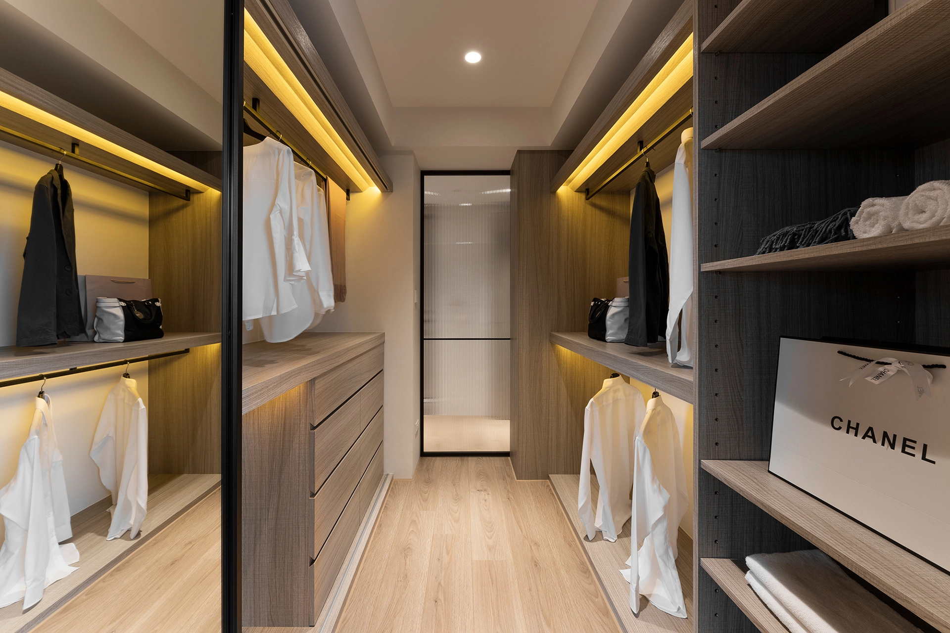 Well-organized walk-in closet with wood finishes and accent lighting. Well-organized walk-in closet with wood finishes and accent lighting.