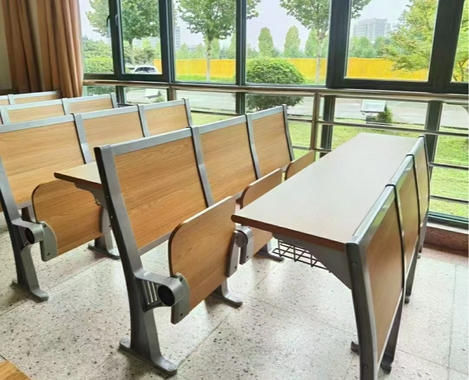 Classroom desks and chairs arranged next to a large window overlooking trees and buildings.
