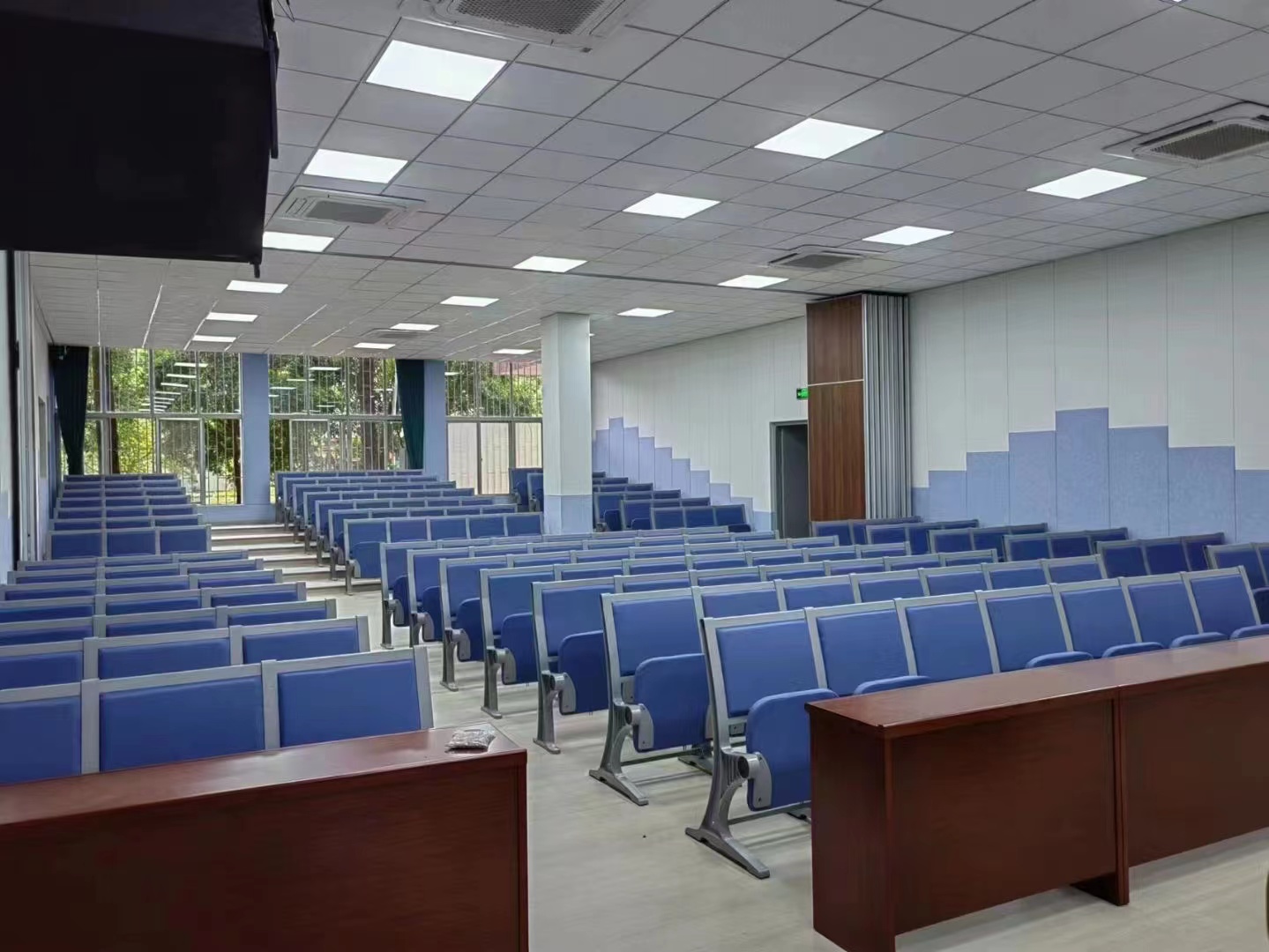 Empty lecture hall with blue seating and tiered rows.