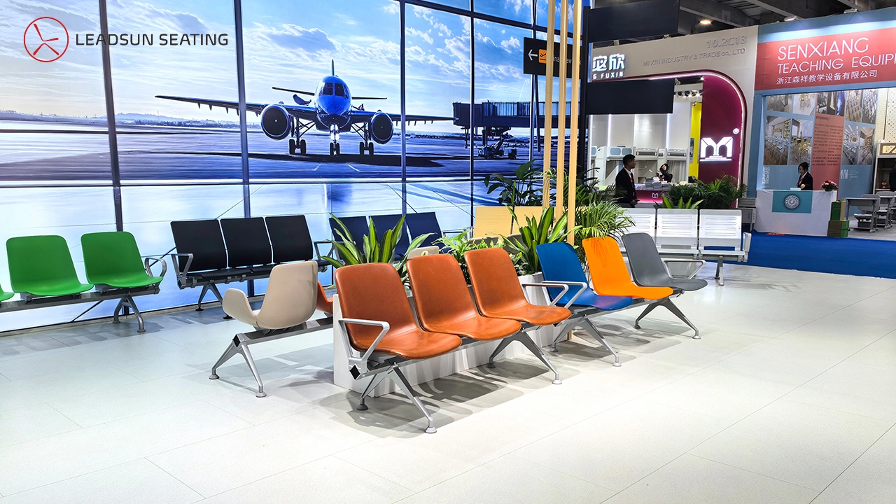 Rows-of-colorful-airport-style-seating-are-displayed-at-a-trade-show-booth-with-an-airplane-backdrop. Rows of colorful airport-style seating are displayed at a trade show booth with an airplane backdrop.