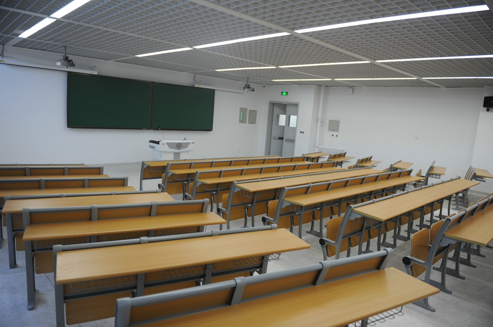 Empty classroom with multiple rows of desks and chairs, a large chalkboard, and a projector. Empty classroom with multiple rows of desks and chairs, a large chalkboard, and a projector.