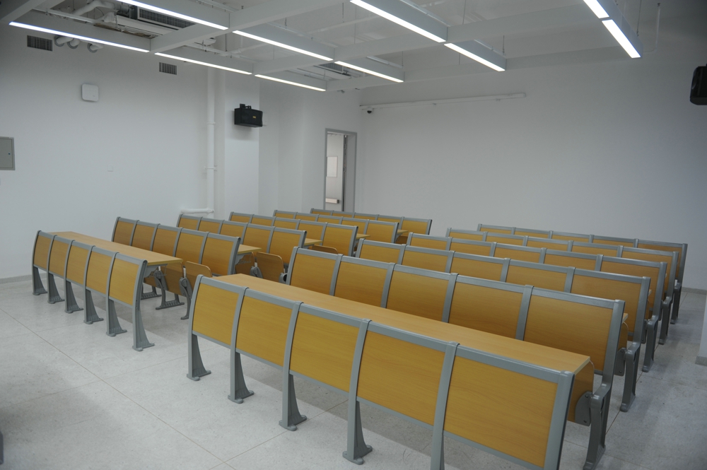 Empty classroom with rows of light brown student desks and chairs. Empty classroom with rows of light brown student desks and chairs.