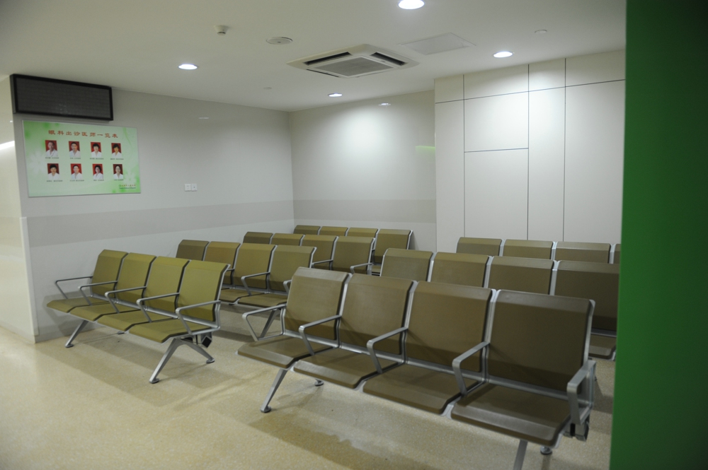 A waiting area with rows of light brown chairs in a modern medical facility. A waiting area with rows of light brown chairs in a modern medical facility.