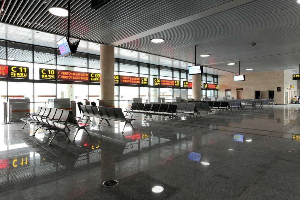 Modern, bright waiting area with rows of empty metal chairs and digital signage displaying departure information in a Chinese train station. Modern, bright waiting area with rows of empty metal chairs and digital signage displaying departure information in a Chinese train station.