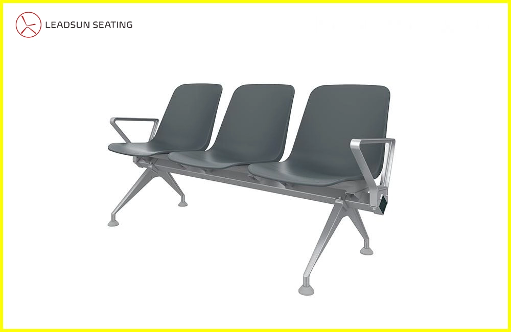 public-metal-waiting-chair Three-seater waiting bench with dark gray plastic seats and a silver metal frame. Each seat has a small armrest.