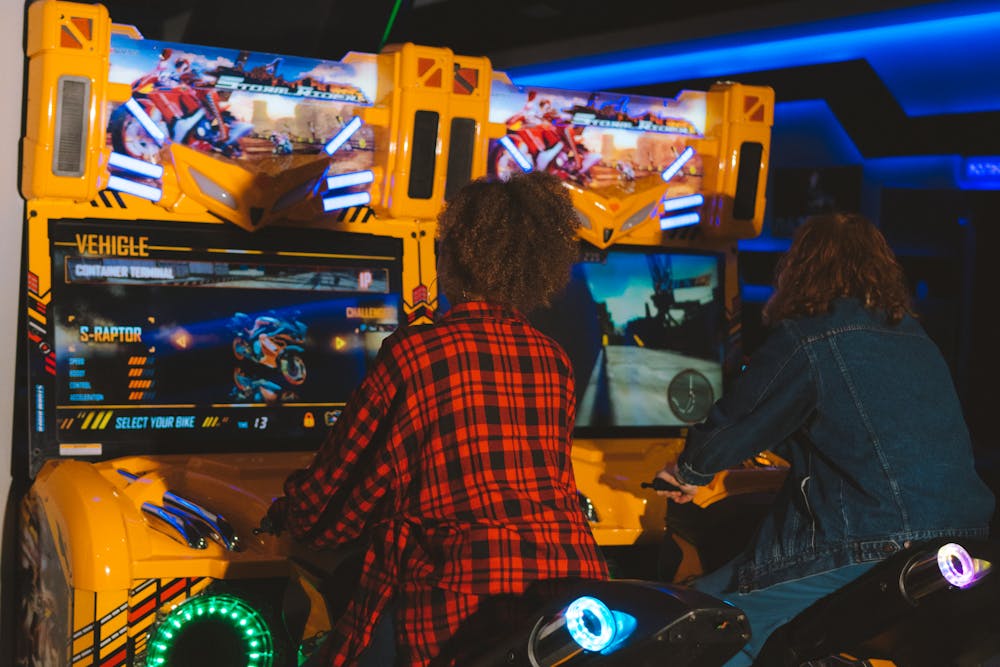 Two people playing a motorcycle arcade game.