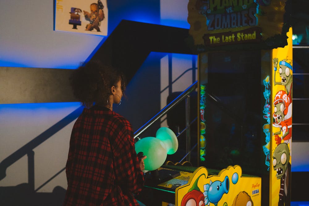 Woman in a red plaid shirt playing the Plants vs. Zombies: The Last Stand arcade game.