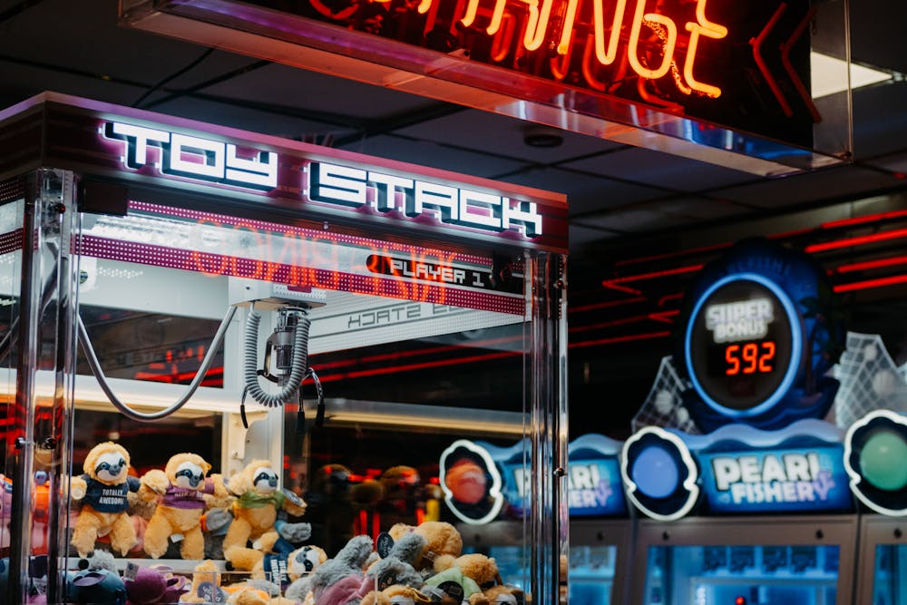 Illuminated claw arcade machine with plush toys inside.