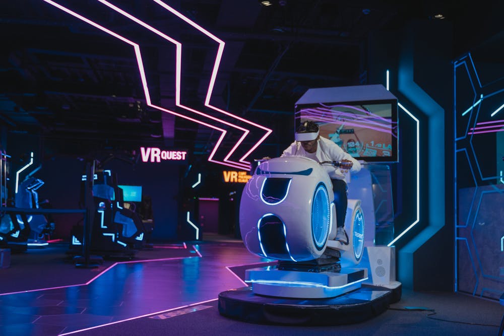 Persona utilizando un simulador de carreras de realidad virtual en una sala de juegos iluminada con luces de neón.