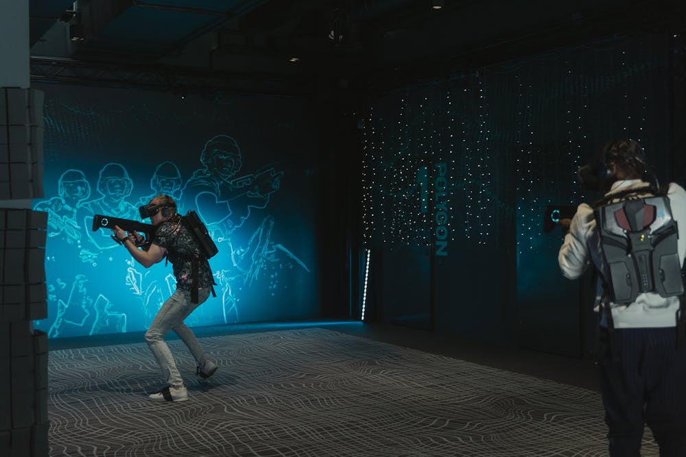 Los jugadores juegan un juego arcade de realidad virtual con auriculares y pistolas de utilería.