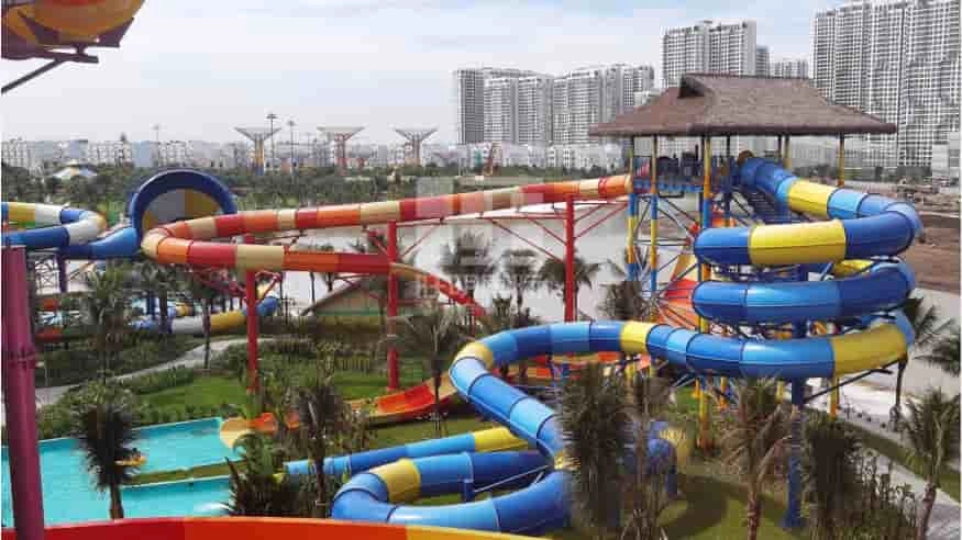 Colorful water slides at a vibrant water park with city buildings in the background. - WM International