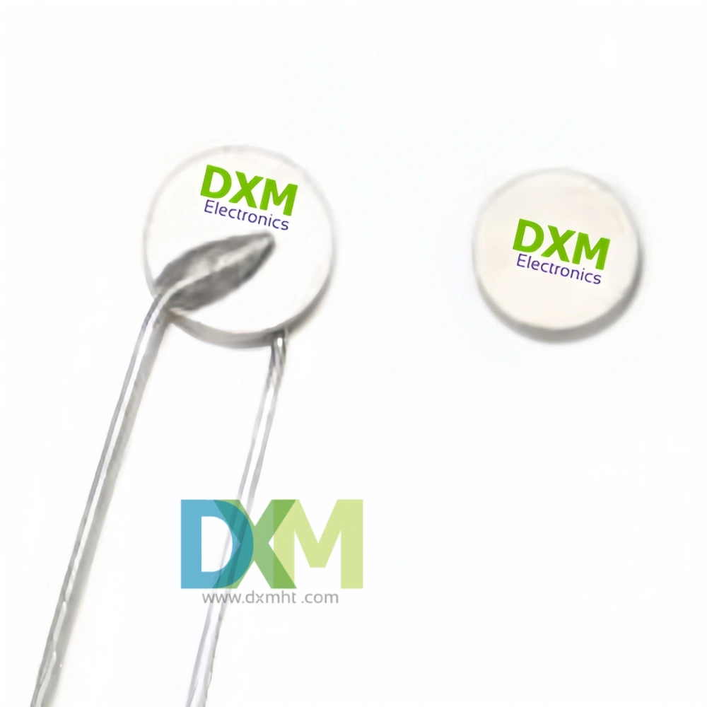 Two round white Thermistor PTC components labeled "DXM Electronics".  The PTC Thermistors are for use in circuit protection of main distribution frame.