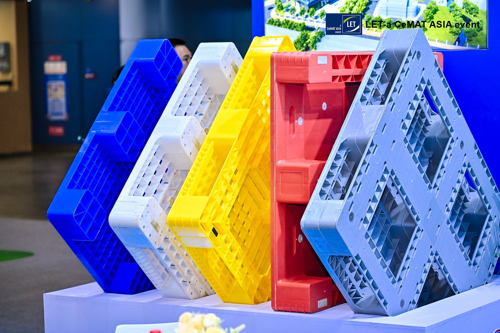 Colorful plastic pallets in blue, white, yellow, red, and grey on display.