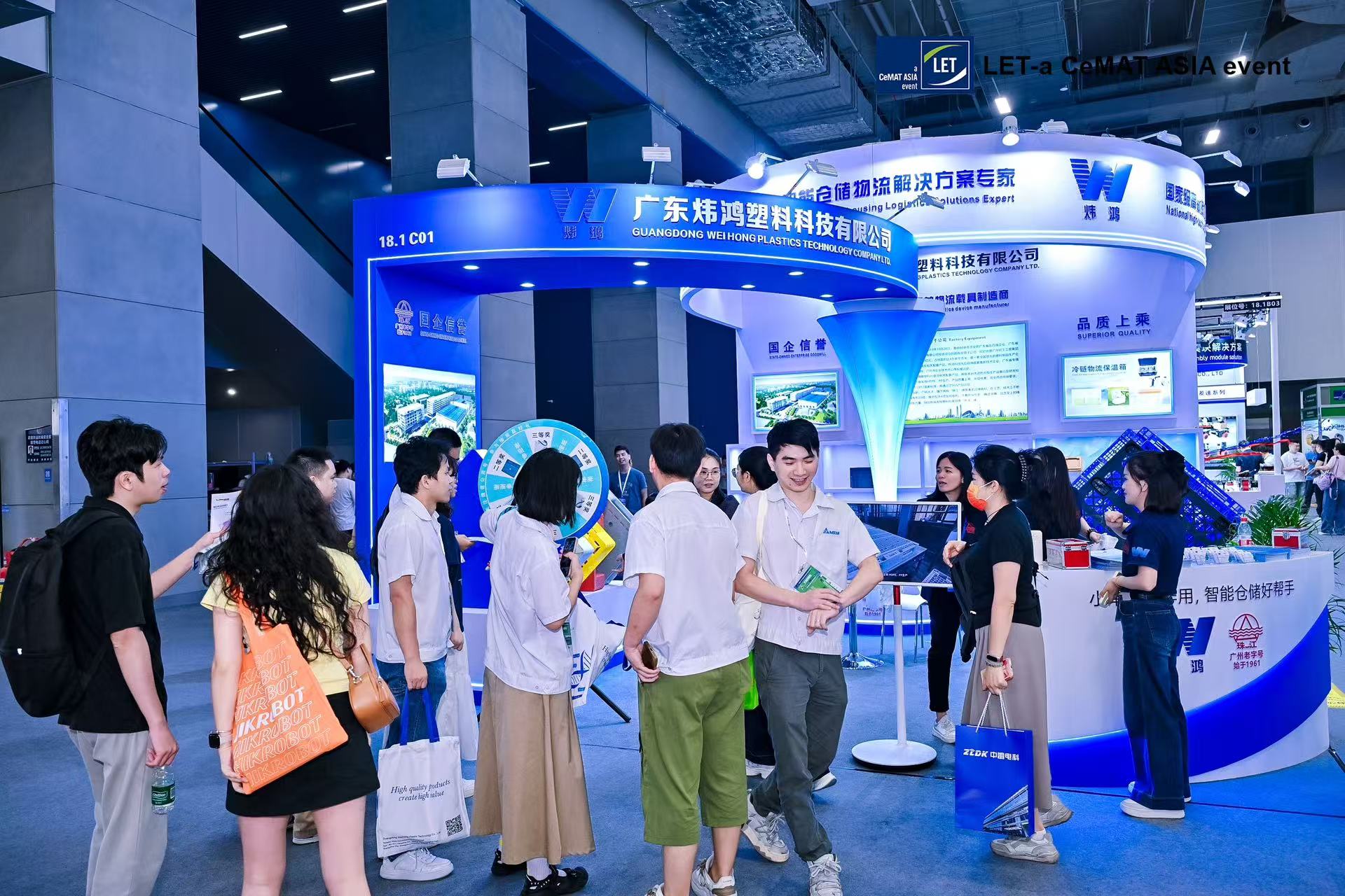 People visiting a blue and white exhibition booth at a trade show event.