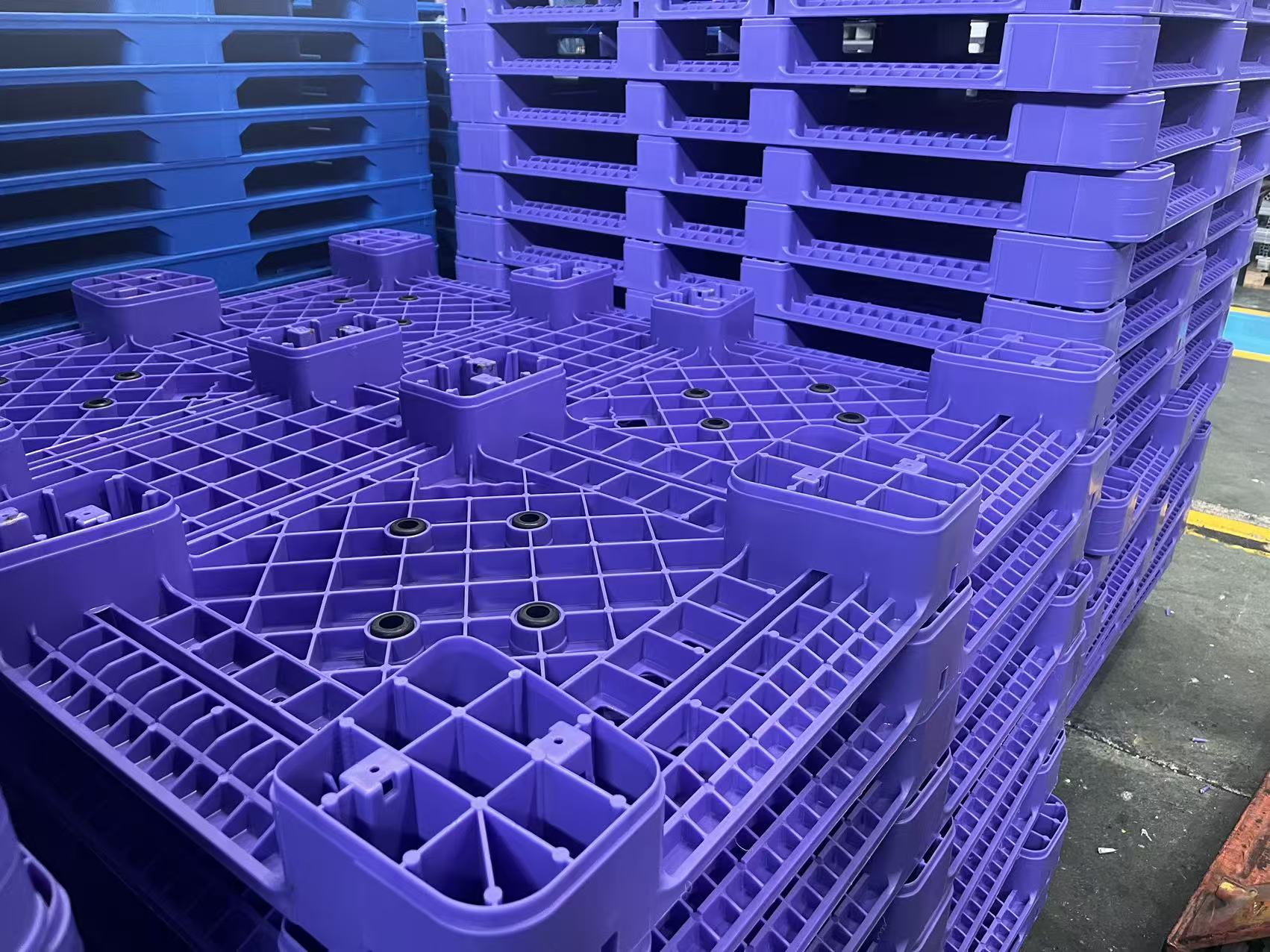 Stacks of purple  heavy-duty plastic shipping pallets in a product.