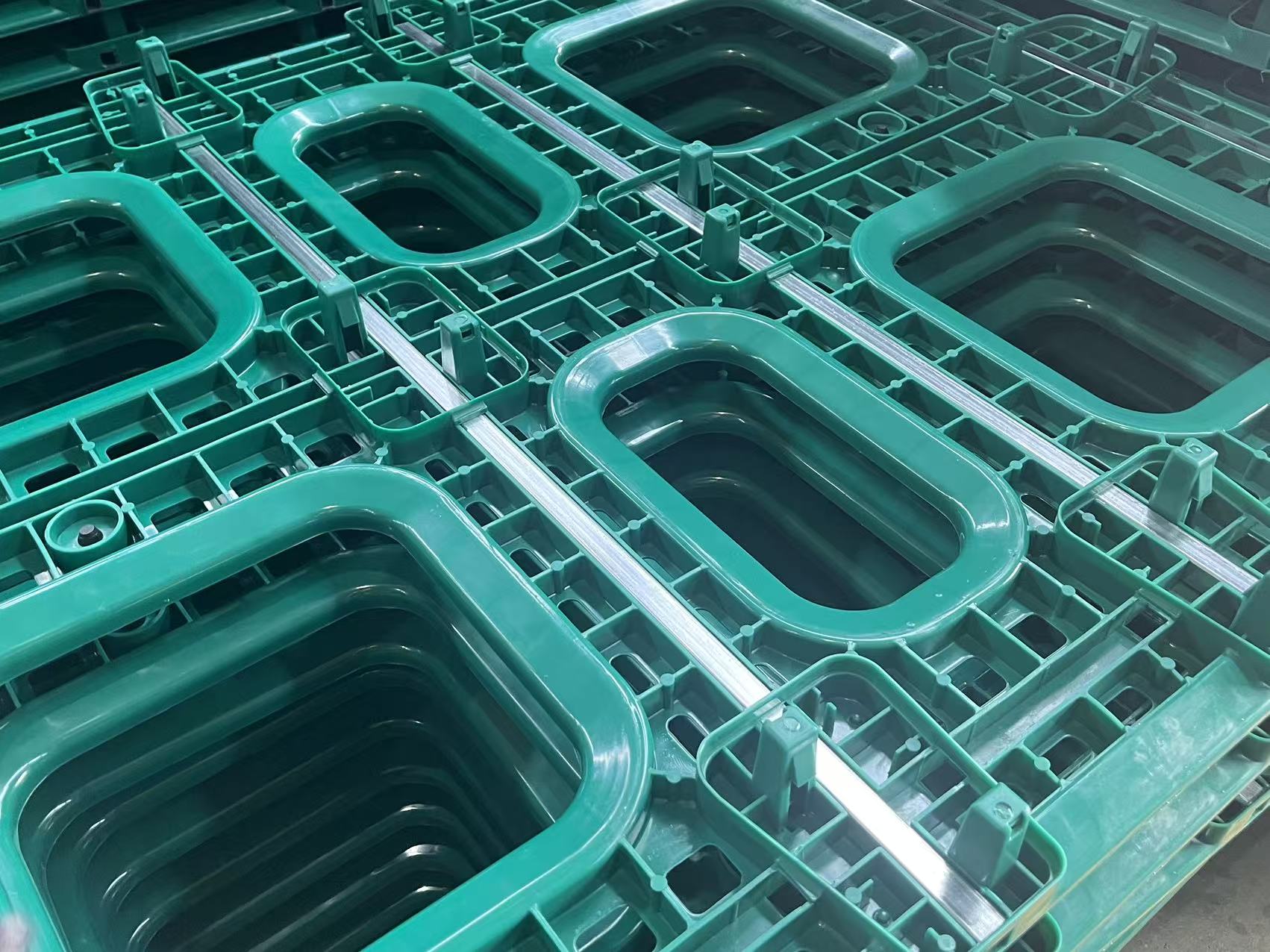 Stacks of green heavy-duty plastic shipping pallets in a product.