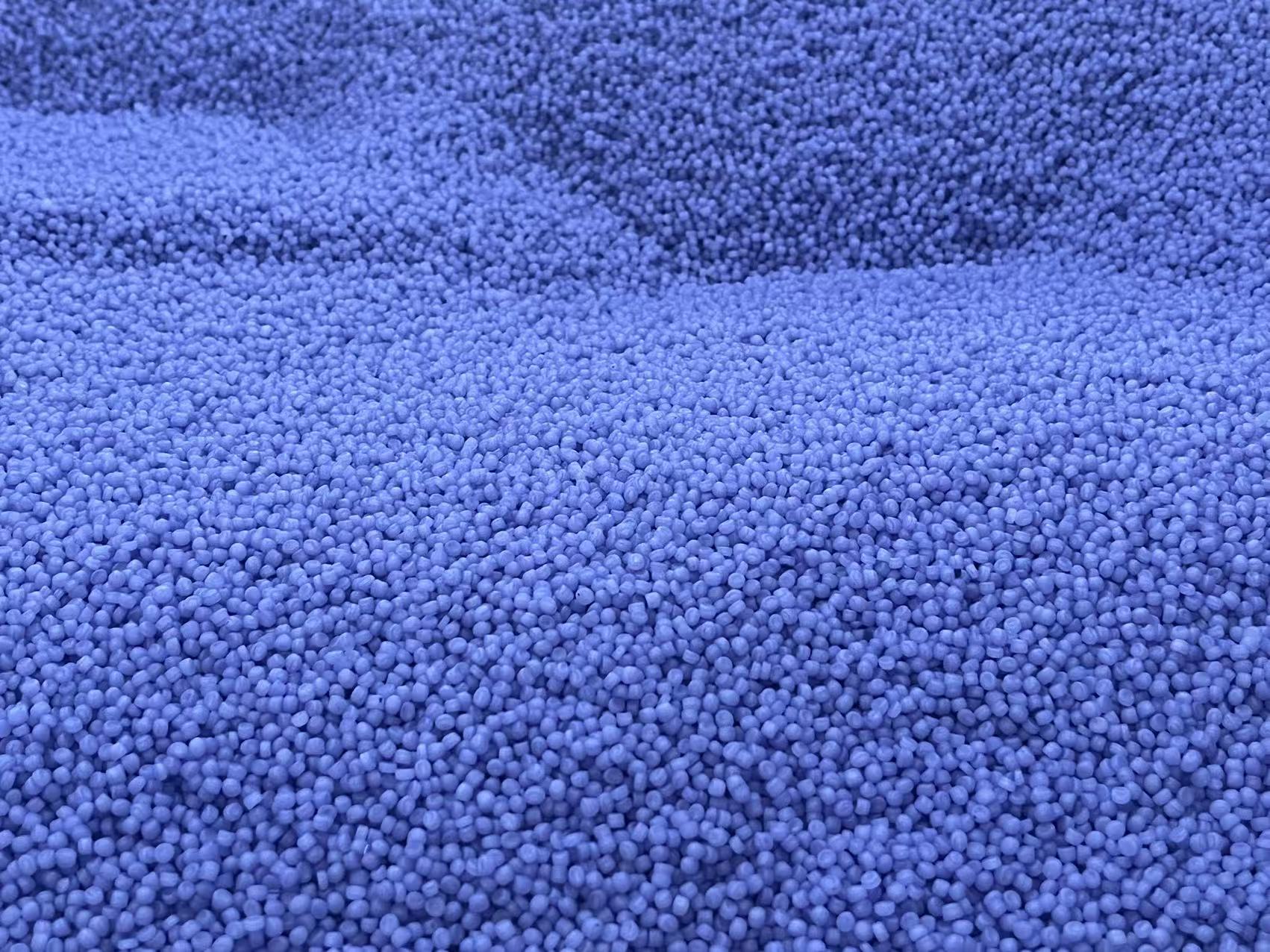 Close-up of a dense pile of small, round purple granular PP material pellets.