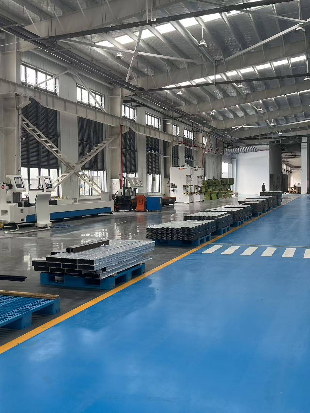 Large industrial factory floor with machinery and metal products on pallets.