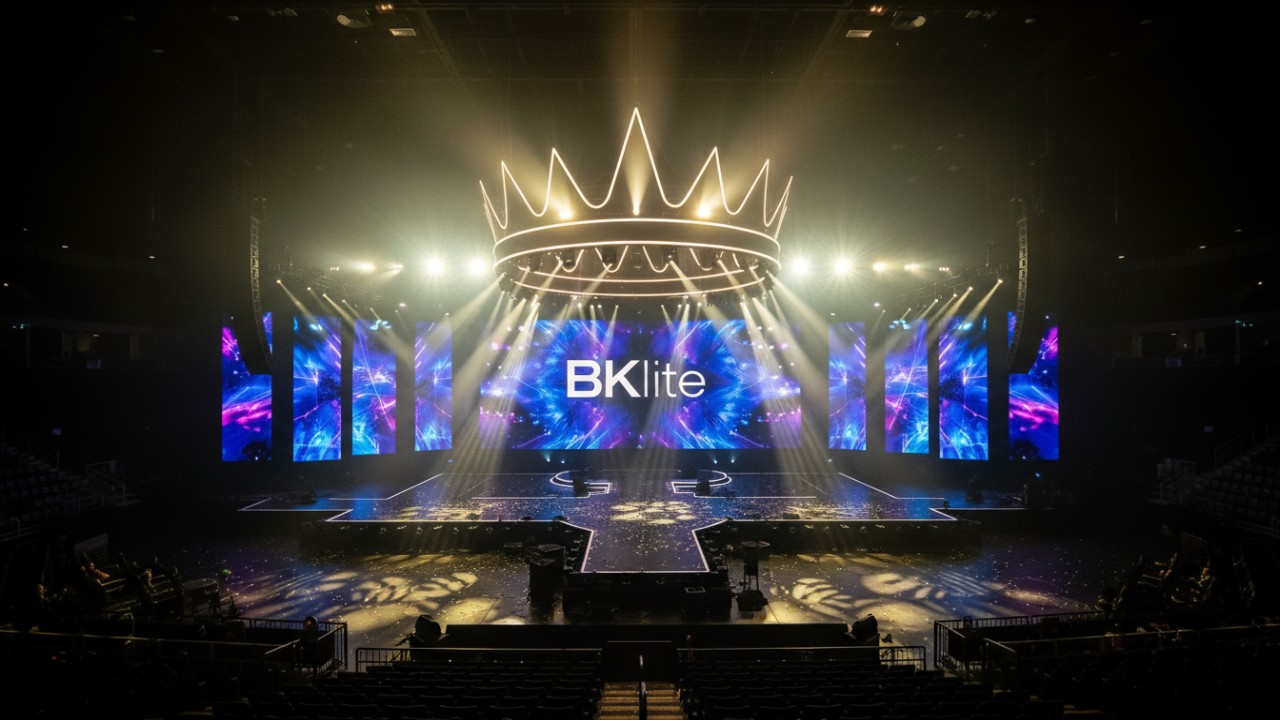 An empty arena stage bathed in spectacular lighting effects with a large BKlite logo displayed on the background screen.