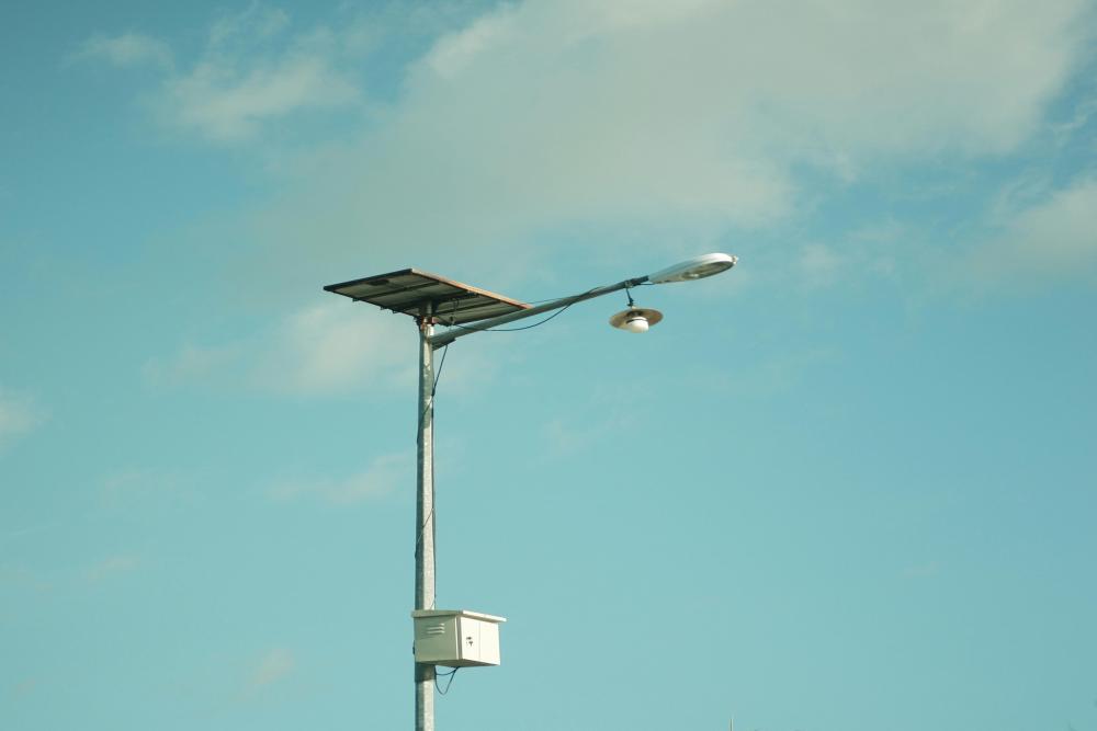 Bulutlu, berrak mavi bir gökyüzüne karşı güneş enerjili bir sokak lambası