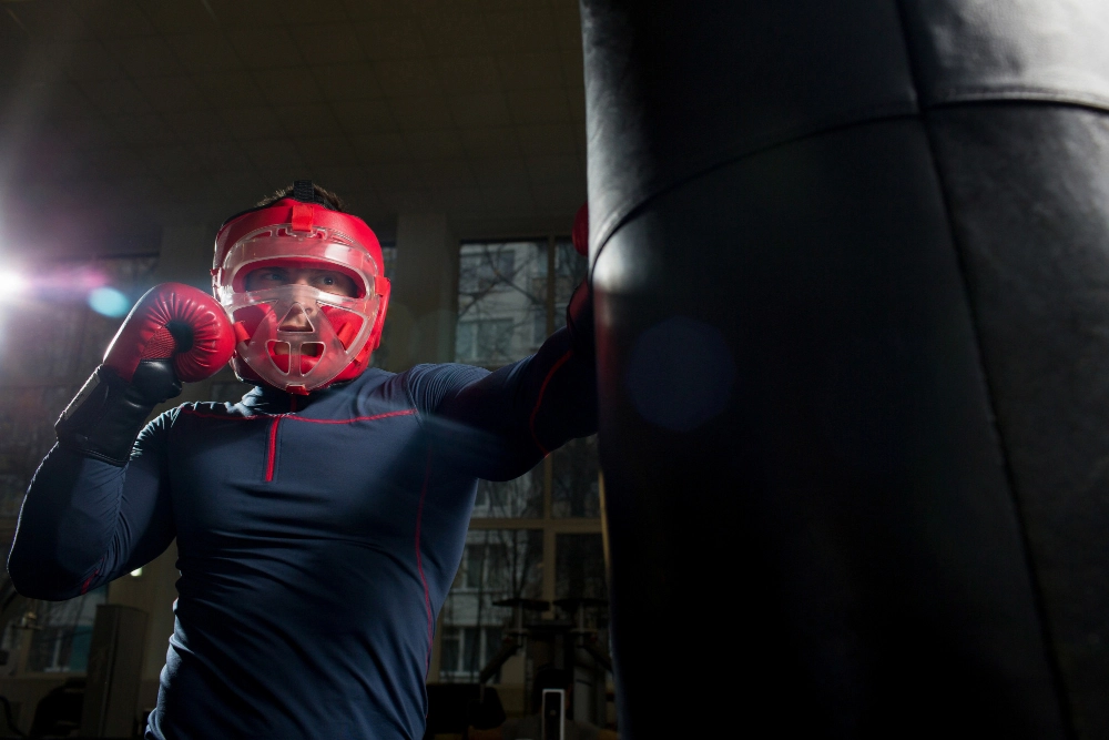 boxer-machine Boxer machine training: athlete in headgear punches heavy bag.