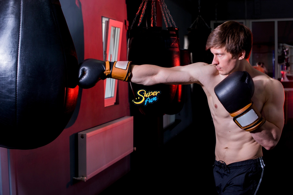 Boxing-Arcade-Machine A muscular man punches a boxing arcade machine in a gym.