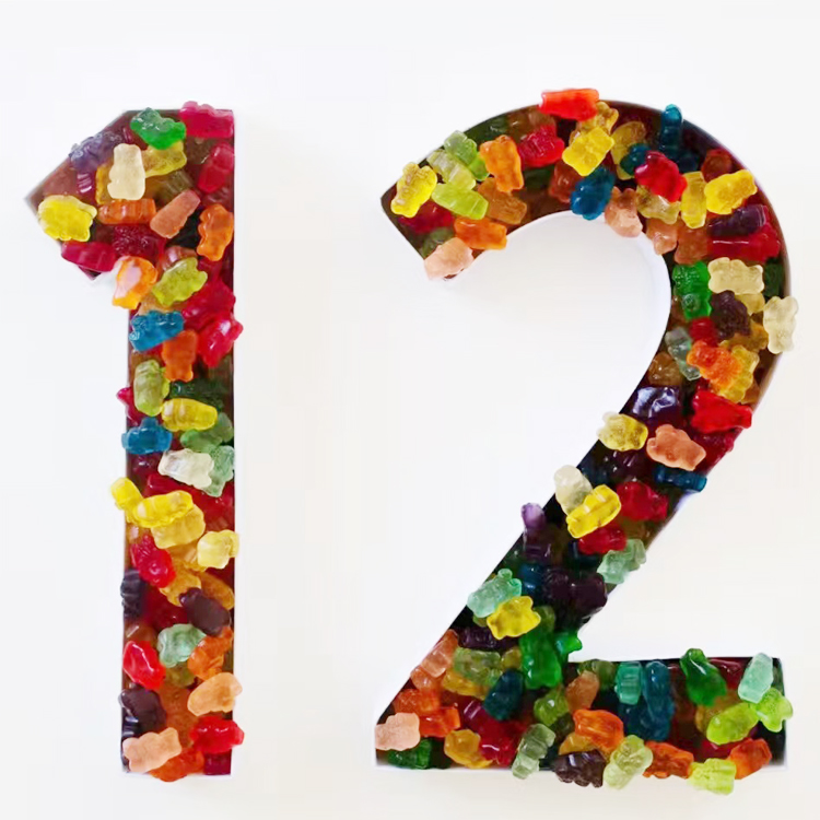 The number 12 filled with colorful gummy bears against a white background.