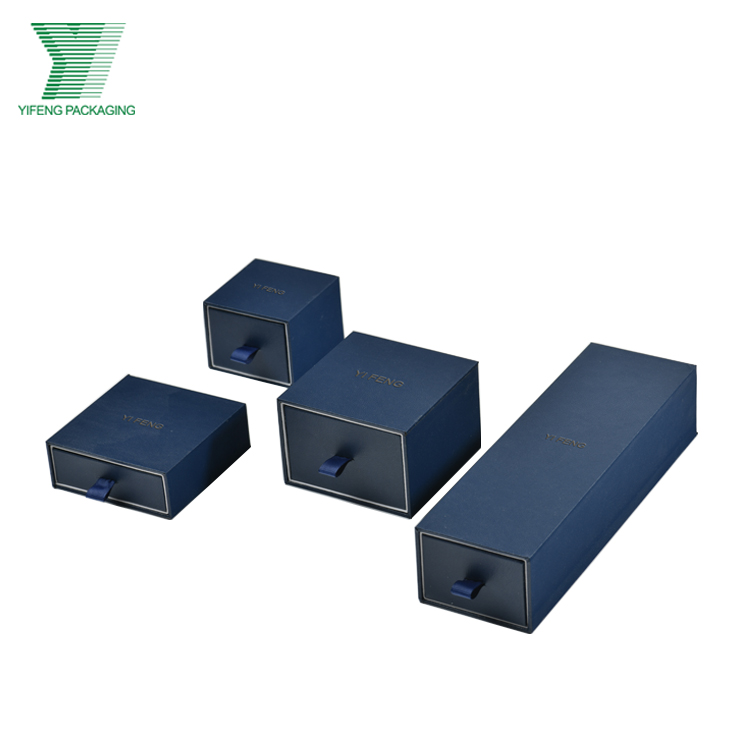 Four blue sliding drawer jewelry boxes in various sizes with ribbon pulls.